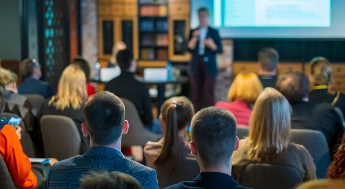 Stock picture showing an group of people listening to a presenter  